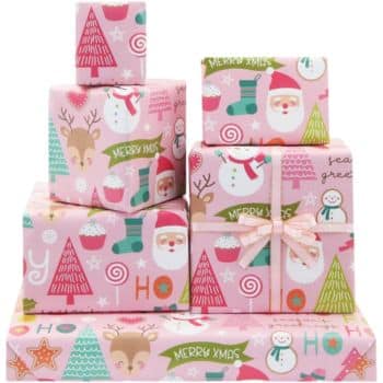 A stack of gift boxes wrapped in pink Christmas-themed paper, featuring Santa Claus, snowmen, reindeer, Christmas trees, and cupcakes, with "Merry Xmas" text and decorative patterns.