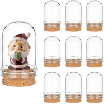 A set of nine transparent glass domes with cork bases, perfect for holiday craft ideas. One dome features a small Santa figurine holding a gift, while the others await your creative touch.