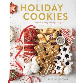 A cookbook cover titled "Holiday Cookies" by Brian Hart Hoffman showcases the best Christmas cookies. The assortment includes gingerbread figures, red and white swirled cookies, snowflakes, candy canes, and sprinkles all artfully arranged on a pristine white background.