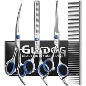 A grooming kit featuring four silver pet grooming scissors with blue accents and a black handle comb, all displayed in front of a black box with white text.