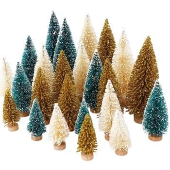 A collection of small, decorative bottle brush Christmas trees in green, gold, and white offers festive holiday craft ideas. The trees vary in height and are dusted with white to mimic snow, arranged randomly on a flat surface.