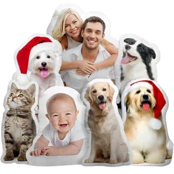 A smiling couple and a baby surrounded by four dogs and a cat. Two dogs are wearing Santa hats. The animals are in a playful pose, adding a festive touch to the joyful scene.