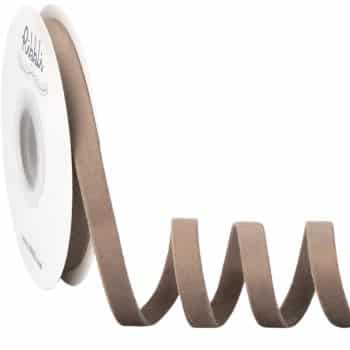 A spool of brown ribbon is unwound in a loose coil, lying on a white surface with the label partially visible.