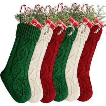 Six Christmas stockings in alternating green, cream, and red colors are filled with candy canes and greenery, arranged in a row.