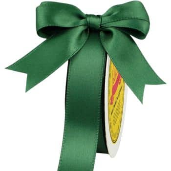 A spool of dark green satin ribbon tied into a large, decorative bow. The bow has long, elegant tails, and the ribbon is wound around a cylindrical cardboard reel with a yellow label.