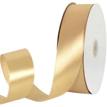 A spool of shiny gold ribbon partially unwound, with the ribbon smoothly cascading down beside it. The ribbon appears glossy, reflecting light, contrasting with the matte grayish background.