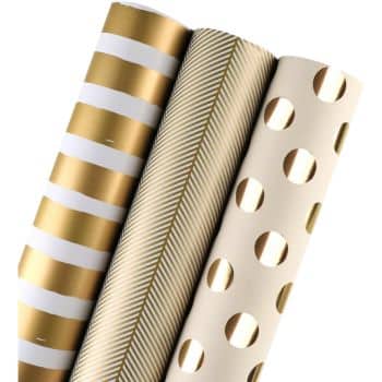 Three rolls of wrapping paper stand upright. The designs include gold and white stripes, herringbone patterns, and polka dots.