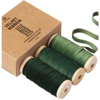 A set of three spools of green velvet ribbon next to a brown cardboard box labeled "Velvet Ribbon." The ribbons vary in shades from light to dark green, with one ribbon partially unrolled.