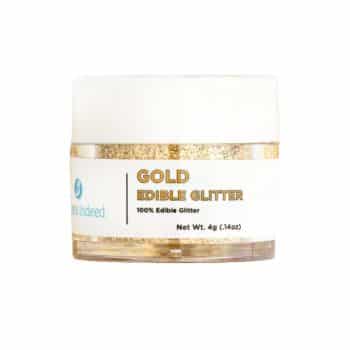 A small jar of gold edible glitter with a white lid, labeled "100% Edible Glitter" and "Net Wt. 4g (0.14oz)," perfect for adding sparkle to New Year's recipes. The brand is displayed on the left side of the label.