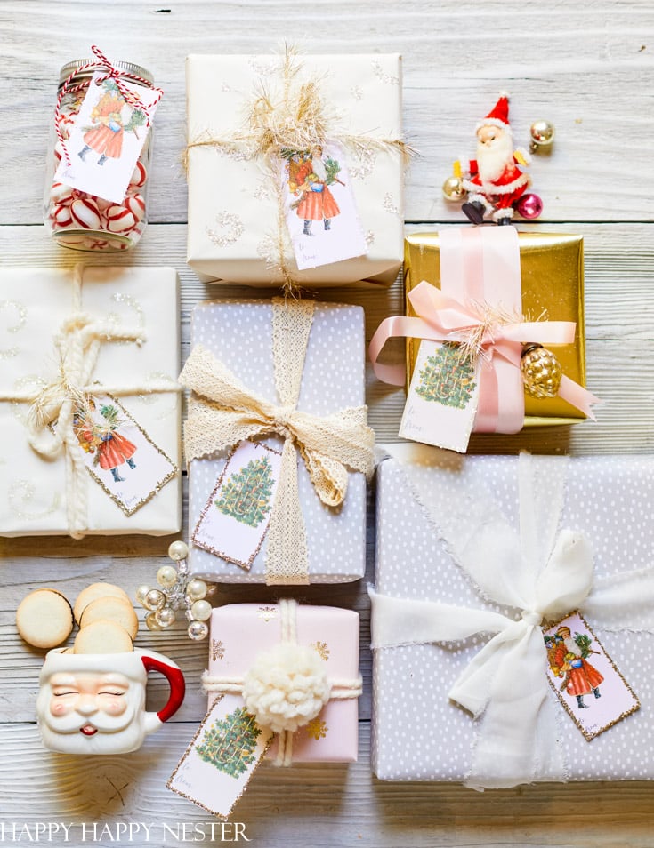 A group of beautifully wrapped presents with cute Christmas tags featuring holiday designs. The packages are adorned with ribbons in various colors and textures. Nearby, a Santa mug filled with cookies and a small Santa figurine add a festive touch.