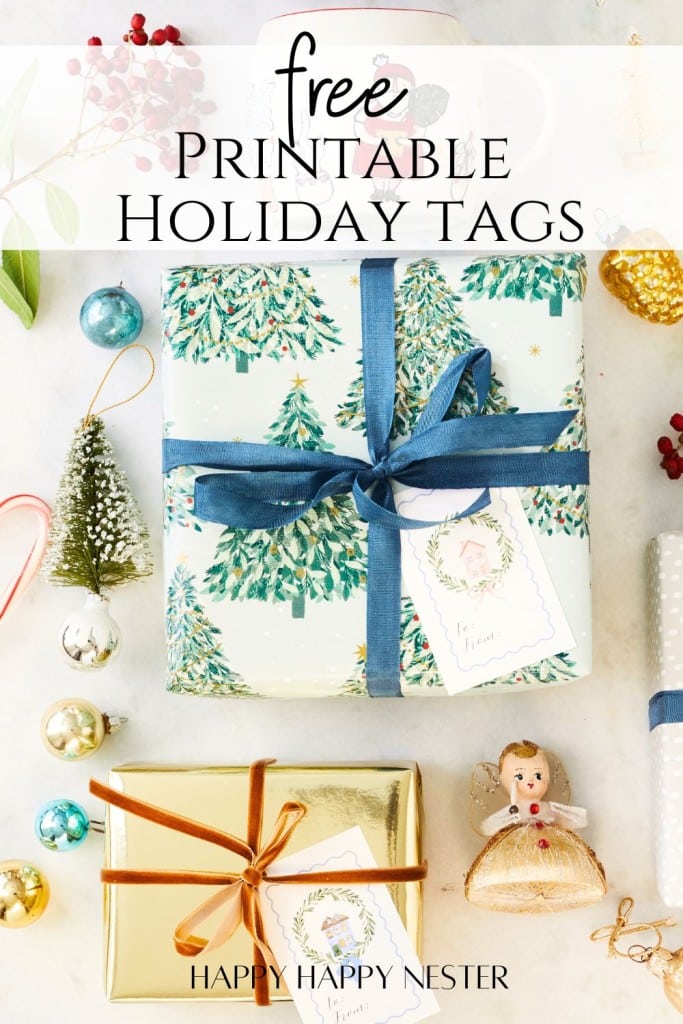 From above, wrapped holiday gifts are showcased—one in green tree-patterned paper with a blue ribbon, another in gold with a brown ribbon. A small tree, ornaments, and an angel figurine add charm. Text reads, "Free Printable Holiday Tags" to complete the festive look.