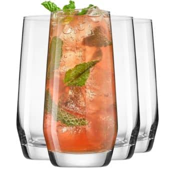 A clear glass filled with a fizzy pink drink, ice cubes, and mint leaves hints at refreshing new year's recipes. Three empty glasses await the next pour.