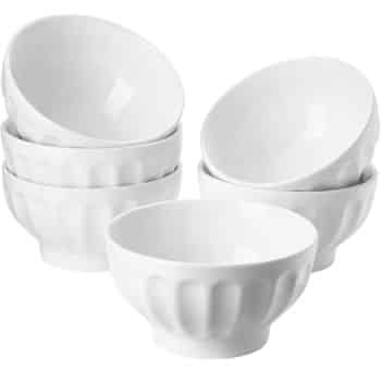 Six white ceramic bowls stacked in pairs, perfect for serving your favorite New Year's recipes. With a smooth, glossy finish, these bowls boast a simple, modern design featuring slightly flared rims and a patterned exterior.