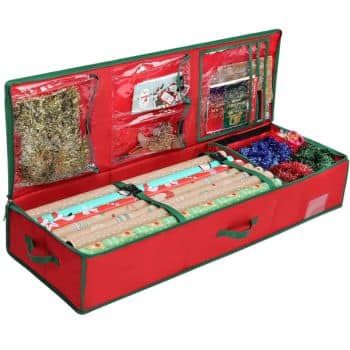 A red and green storage organizer holds various Christmas wrapping supplies, including cute Christmas tags. It contains rolls of gift wrap, ribbons, and compartments with clear pockets filled with decorations and accessories.