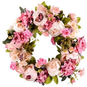 A circular floral wreath featuring a mix of pink and white roses, peonies, and hydrangeas, accented with lush green foliage.