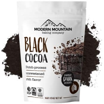 Packaging of Modern Mountain Baking Company Black Cocoa, featuring Dutch-process, unsweetened cocoa with rich flavor perfect for recipes made with chocolate chips. The label shows a chocolate cake illustration against a background of cocoa powder. Net weight is 16 oz (454 g).