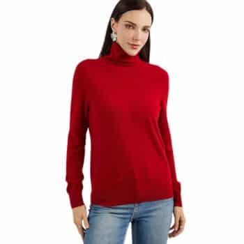 A person with long dark hair is wearing a red turtleneck sweater and blue jeans. They are standing with hands on their sides against a white background.