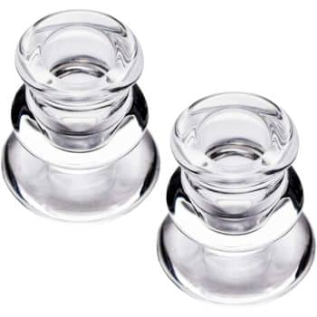 Two clear glass candle holders with a smooth, rounded design. The holders are set on a plain white background, showcasing their transparent and reflective surfaces.