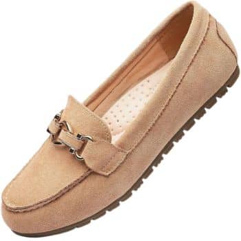 A tan suede loafer with a decorative metal buckle on top. The shoe has a rubber sole with a textured grip.