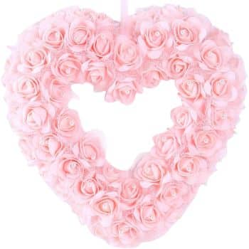 A heart-shaped wreath is covered with numerous pink roses, featuring a small open heart space in the center. Each rose is detailed and uniform, creating a delicate and romantic appearance.