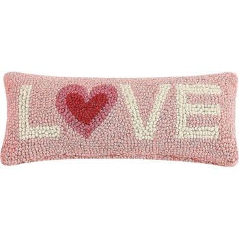 A rectangular, textured pink pillow with the word "LOVE" in cream letters. The "O" is replaced with a red heart shape.