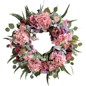 A floral wreath featuring pink and purple roses, hydrangeas, and greenery arranged in a circular design.