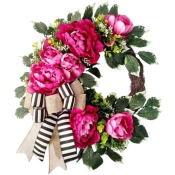 A vibrant wreath featuring bright pink peonies and lush green leaves. It is adorned with a burlap and black-and-white striped ribbon bow at the bottom, creating a cheerful and elegant look.