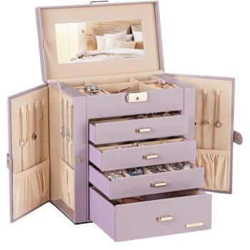 A lavender jewelry box with an open lid and mirror. It has multiple pull-out drawers and compartments, displaying various pieces of jewelry such as necklaces and rings. The interior is a soft beige color.