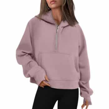 A person wearing a light purple pullover hoodie with a zip-up collar, long sleeves, and a front pocket, paired with black pants. The person's hair is loose, and their arm is bent, with their hand in the pocket.