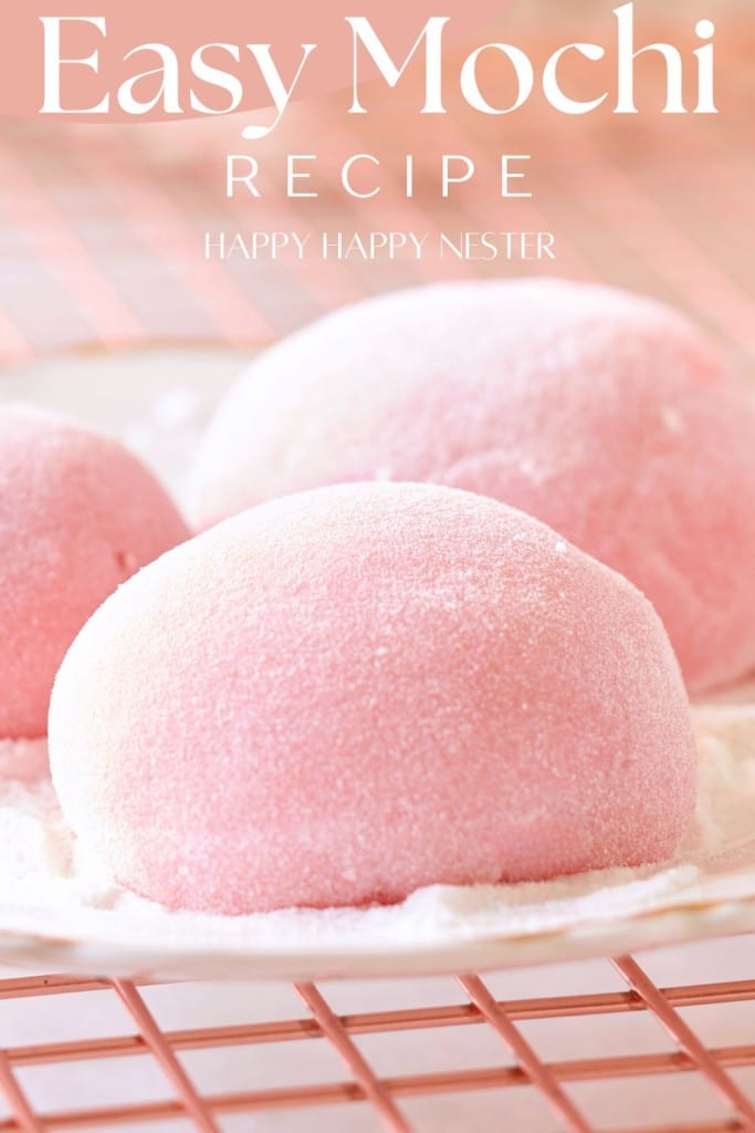 Close-up of three pink mochi balls on a white plate, delicately dusted with powdered sugar. The text "Easy Mochi" and "Happy Happy Nester" graces the top, set against a gentle pink grid background.