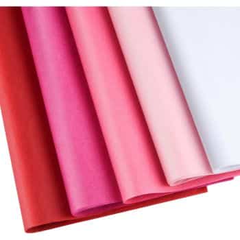 A neatly arranged stack of tissue paper, perfect for pink crafts, showcases various shades including red, fuchsia, pink, light pink, and white. The papers are positioned vertically, creating a gradient effect from left to right.