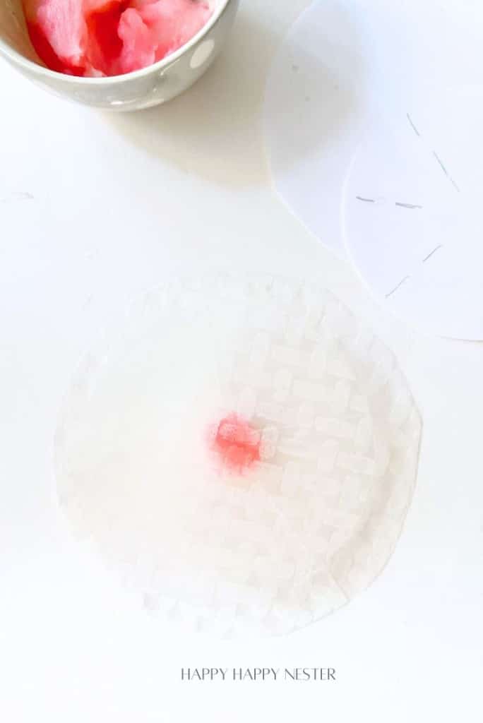 A delicate circular sheet, resembling rice paper, is spread on a white surface, adorned with a small red flower petal in the center. Nearby sits a bowl filled with pink and white accents. The text "HAPPY HAPPY NESTER" completes this scene of elegance reminiscent of fried rice paper flowers.