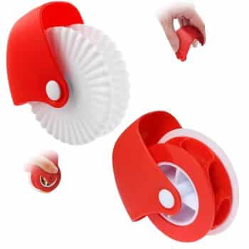 The red and white pastry cutter, ideal for crafting decorative edges on my favorite desserts, features a fluted wheel design. Its red handle with a white button pivot point is showcased in the image, demonstrating its ergonomic grip as it's held confidently in hand.