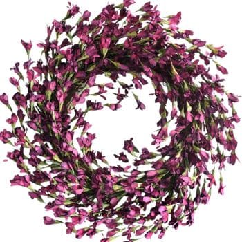 A wreath made of small, purple flowers arranged in a circular pattern. The flowers have green stems, adding contrast. The background is white, highlighting the vibrant purple hues of the floral arrangement.