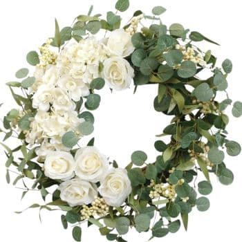 A circular wreath made of green eucalyptus leaves, white roses, and small white flowers and berries. Half of the wreath is more densely packed with flowers, creating an elegant and balanced design.