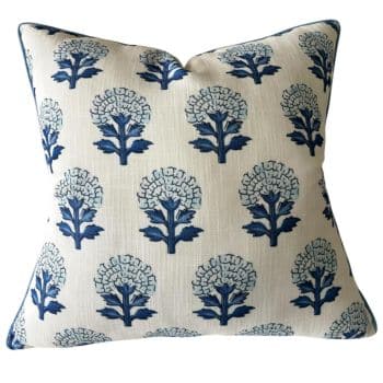 A square throw pillow with a pattern of blue floral designs on a white background. The flowers are arranged in neat rows, each featuring stylized stems and leaves. The pillow has dark edging that contrasts with the lighter fabric.