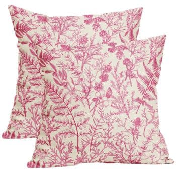 Two square pillows featuring a floral and fern pattern in pink on a cream background. The design has intricate leaves and flowers, giving a natural and elegant look. The pillows are placed against a white backdrop.