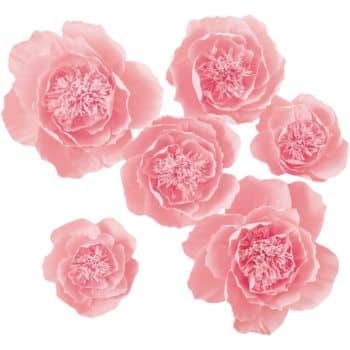 Seven pink peony flowers, reminiscent of easy flower paper crafts, are scattered against a white background. The flowers vary in size and display layers of delicate, ruffled petals with intricate centers.