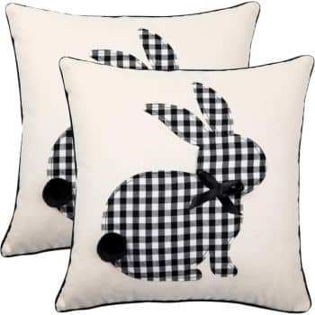 Two square pillows with black and white checkered rabbit silhouettes. Each rabbit has a small black bow at the neck and a pom-pom tail. The pillows have a light background with dark trim.