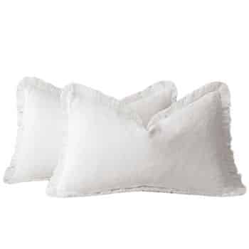 Two white rectangular pillows with fringed edges, positioned overlapping each other on a plain background.