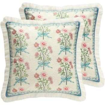 Two decorative pillows with a floral pattern featuring pink flowers and green leaves tied with blue ribbons. The design is enclosed within a blue and white border, and each pillow has a ruffled edge.