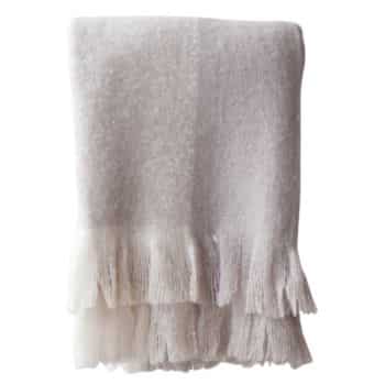 A soft, off-white blanket with fringed edges, folded neatly.