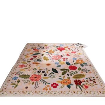 A rectangular rug with a beige background features a colorful floral pattern, including red, pink, yellow flowers, and green leaves. The design is bordered by a simple floral motif.