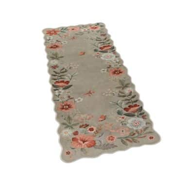 A rectangular rug with scalloped edges featuring a floral pattern with red, pink, and white flowers and green leaves on a beige background.