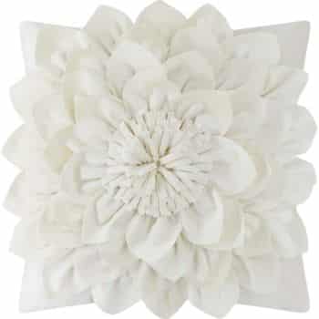 A decorative pillow featuring a large, intricate white floral design with layered petals. The petals are arranged symmetrically, creating a three-dimensional effect. The pillow is square, with the flower centered prominently.