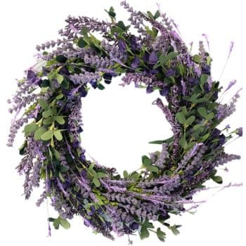 A circular wreath made of lavender flowers and green leaves. The arrangement features purple hues and lush foliage, creating a natural and elegant appearance.