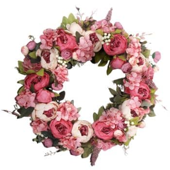 A decorative wreath made of pink and white peonies, hydrangeas, and various greenery arranged in a circular shape. The flowers are lush and vibrant, creating a fresh and elegant appearance.