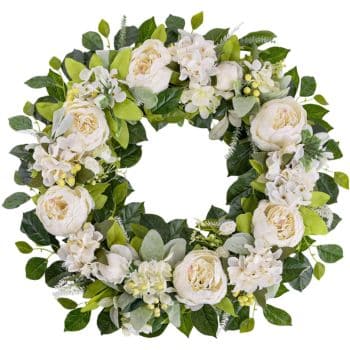 A decorative wreath with white roses and assorted greenery, including leaves and small flowers, arranged in a circular pattern.