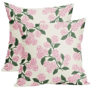 Two square pillows with a floral design feature pink blossoms and green leaves on a white background.