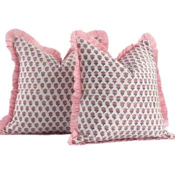 Two decorative pillows with a floral pattern featuring small purple flowers on a white background. They have pink ruffled edges, adding a touch of elegance and softness. Placed upright, showing off their detailed design.